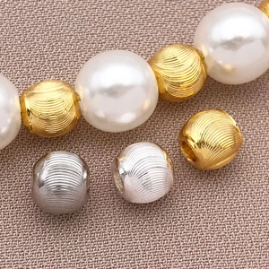 Detailed macro of 18k gold plated cat-eye copper beads and pearls on linen fabric