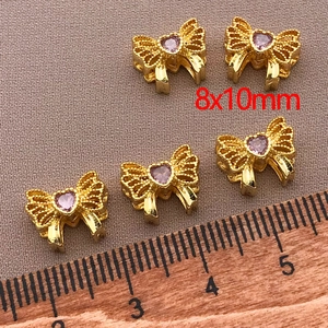 Macro shot of 18K gold plated bow beads with pink zirconia for jewelry making