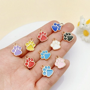 Macro detail of colorful enamel cat paw charms with gold plating held in a hand for DIY crafts