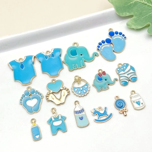 Set de dijes esmaltados de bebé en azul y dorado con mamelucos y biberones en plato blanco