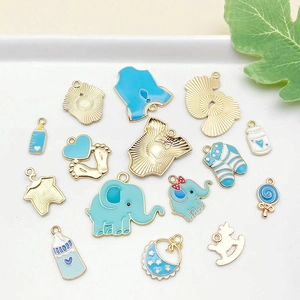 Detalle de dijes esmaltados azules con motivos de bebé y biberón para creación de joyas
