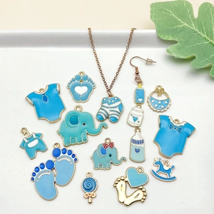 Set de dijes esmaltados azules para bebés con biberones y ropa en fondo blanco