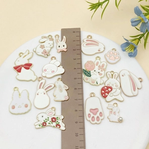 Set of white enamel rabbit and cat paw charms with a ruler for scale measurement