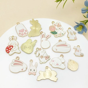 Detailed view of white enamel rabbit pendants with golden metal edges for jewelry making