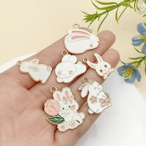 Macro detail of white enamel rabbit charms for DIY jewelry making with gold-plated alloy