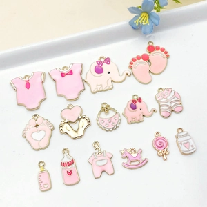 Detalle de dijes de bebé de esmalte rosa y dorado incluyendo babero y biberón