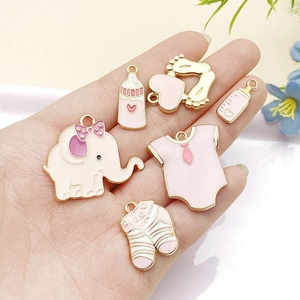 Detalle de dijes de esmalte rosa con elefante, biberón y huellas de bebé para joyería DIY