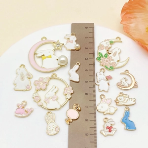 Flat lay of pastel enamel Easter pendants with pearls and ruler for size scale