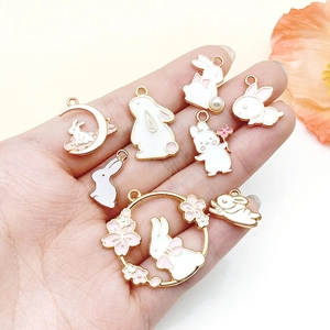 Detailed palm view of eight assorted cartoon rabbit charms with white enamel and pearls