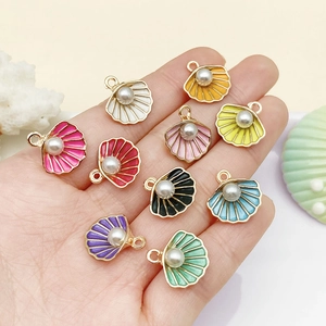 Macro shot of colorful shell charms with pearls held in hand for jewelry DIY