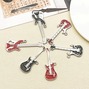 Set of six varied guitar and bass pendants with colorful enamel finish on a beige tray
