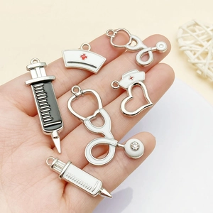 Detailed view of medical charms showing syringe and stethoscope on palm for size