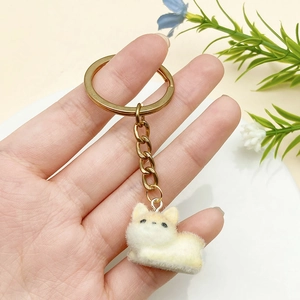 Detailed view of a creamy yellow flocked puppy keychain with a golden metal ring