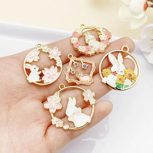 Detail shot of five colorful enamel bunny pendants with gold frames for DIY jewelry crafts
