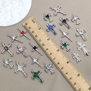 Makroaufnahme von bunten Strass-Kreuzanhängern auf einem Holzlineal als Größenreferenz