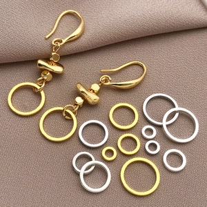18K gold plated copper rings and handmade geometric earrings on textured background