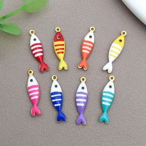 Detailed view of eight colorful enamel fish pendants with white stripes for DIY jewelry making