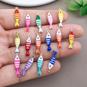 Detail of colorful striped fish charms held in hand showing actual size for DIY jewelry