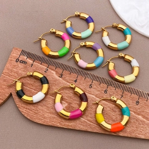 Detail view of 20mm gold bamboo hoop earrings with colorful enamel sections on fabric background
