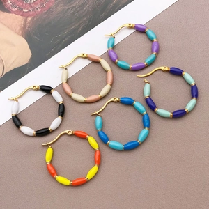 Detail view of six pairs of colorful enamel U-shaped hoop earrings with golden clips