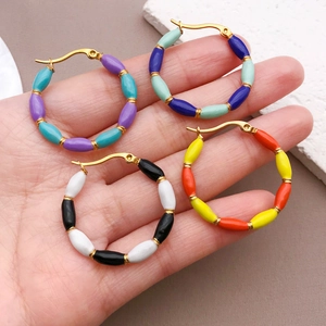Handheld view showing four pairs of colorful beaded gold hoop earrings in palm