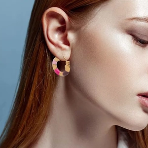 Close-up of a model wearing the colorful bamboo-style enamel hoop earring in gold