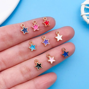 Gros plan de neuf breloques étoiles colorées sur les doigts pour la création de bijoux
