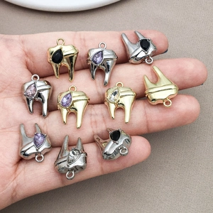 Vista dettagliata di ciondoli a forma di dente in oro e argento con strass colorati