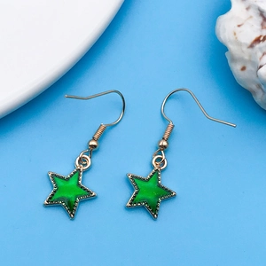 Dettaglio di orecchini a stella verde con ganci dorati su sfondo azzurro stile estivo