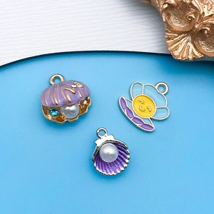 Detalle de dijes esmaltados de colores para creación de joyas DIY con perlas y conchas