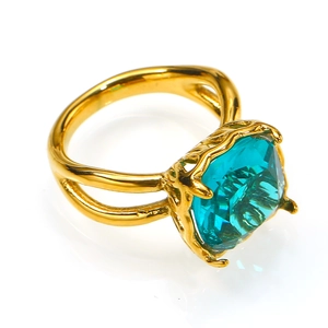 Detalle de anillo cóctel con gema cuadrada verde azulado y garras doradas grabadas