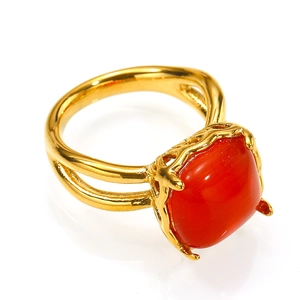 Vista detallada de un anillo dorado con una gran piedra roja cuadrada y textura de rama