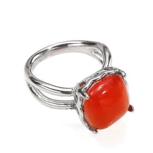 Detalle de anillo con gema roja cuadrada y banda de metal plateado con diseño calado