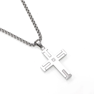 Macro-detail van een hiphop-ketting van titaniumstaal met kruishanger en kleine zirkoon