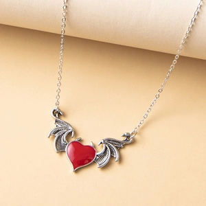 Détail du collier ailes de démon gothique avec pendentif cœur rouge sur fond texturé