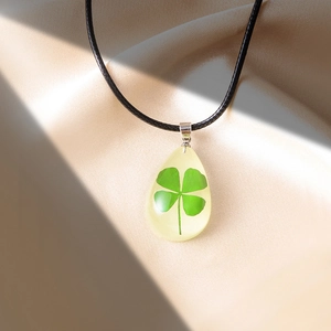 Collana con quadrifoglio in resina trasparente e ciondolo a forma di goccia d'acqua
