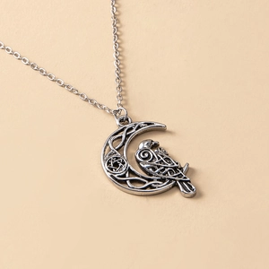 Vintage silver owl and crescent moon necklace with Celtic knot patterns on beige background