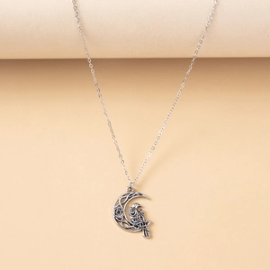 Detail of vintage owl moon necklace with Celtic knot patterns and silver finish