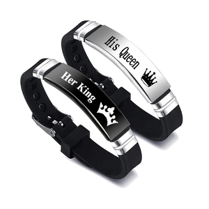 Detail of His Queen and Her King engraved metal plates on black silicone couple bracelets