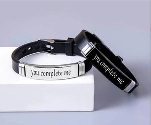 Detail view of couple bracelets with you complete me engraving on metal plates