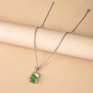 Detailed close-up of clover specimen inside resin pendant with a wish metal tag