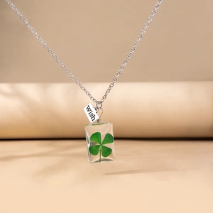 Detail of transparent resin pendant necklace featuring a real four-leaf clover and Wish tag
