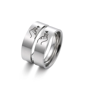 Detailed view of silver stainless steel rings with engraved heart hands gesture