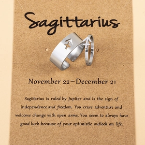 Macro detail of silver Sagittarius couple rings on thematic craft paper card