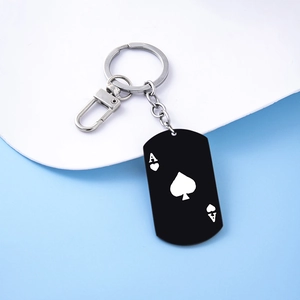 Detail showing matte black metal dog tag keychain with Ace of Spades poker print and lobster clasp