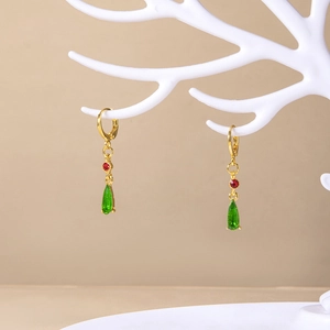 Detail of teardrop earrings with green resin crystal and red gems on a display stand