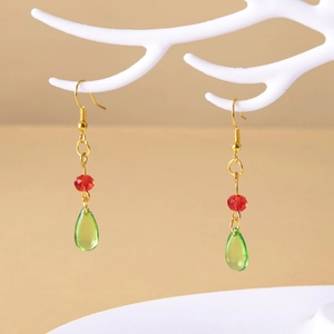 Detail of Howl's Moving Castle green teardrop earrings with red beads on a jewelry stand