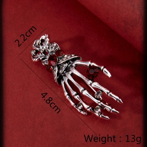 Detailed view of Gothic skeleton hand brooch with red gems and 4.8cm x 2.2cm dimensions
