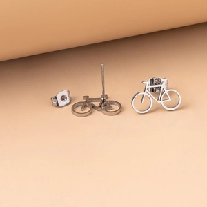 Macro shot of silver bicycle stud earrings with intricate cutout design and backing