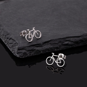 Minimalist silver bicycle stud earrings on black rock with sleek reflective surface